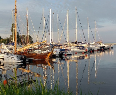 Port Jastarnia z jachtami i pięknymi odbiciami w wodzie, uchwycony w bardzo spokojnych warunkach.